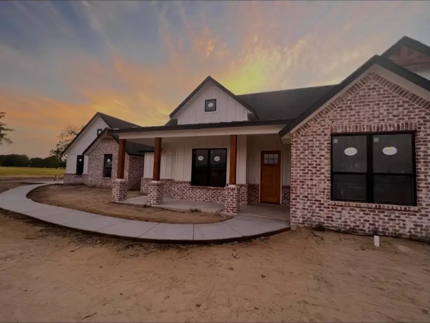 Covered front porch with cedar posts and brick columns on a home built by Elite Solutions of Texas