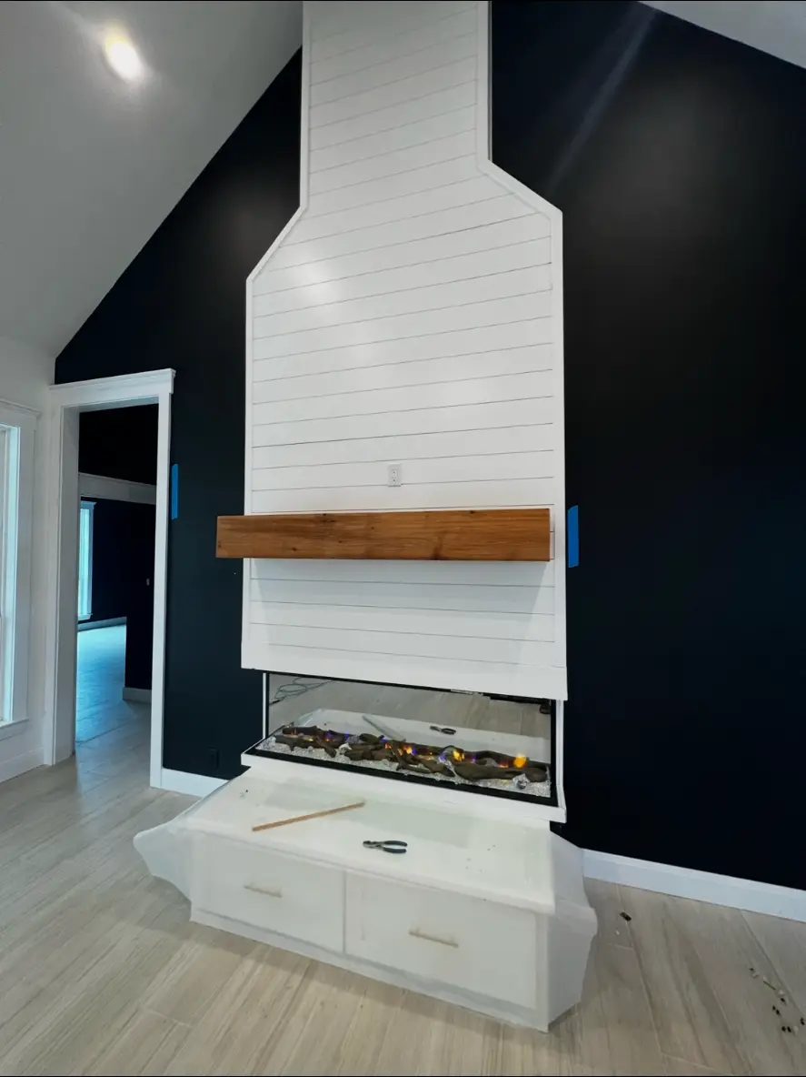 Shiplap fireplace surround with cedar mantel and custom cabinetry finished by Elite Solutions of Texas